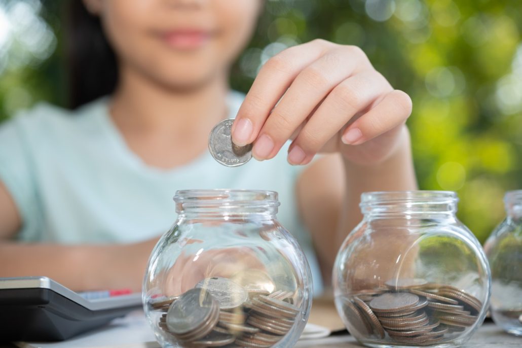 asian little girl saving money in jar