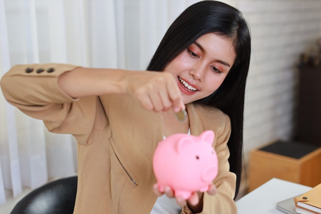 businesswoman putting in coins to piggy bank
